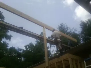 Carpenter setting a ridge beam over a new addition frame — Ice Dam Removal by Roofing Brothers in Stover