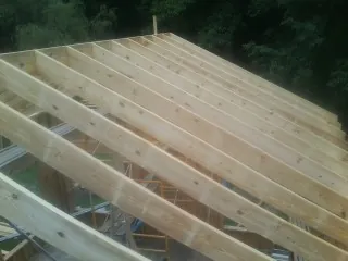 New roof rafters set over an addition before sheathing in Stover