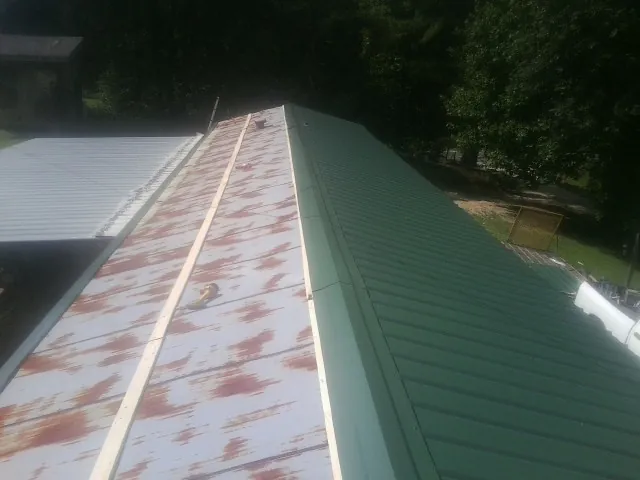 Old rusted panels beside newly installed green metal roofing — Wind Damage Roof Repair by Roofing Brothers in Stover