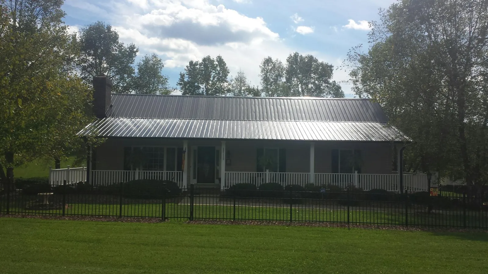 Gray metal roof on a brick ranch with a full width front porch — Gutter Guard Installation work by our crew in Stover