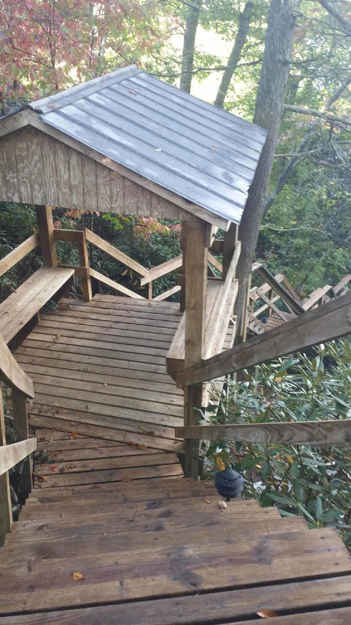 Metal roofed shelter over wooden steps on a wooded walkway — Skylight Repair & Installation work by our crew in Stover