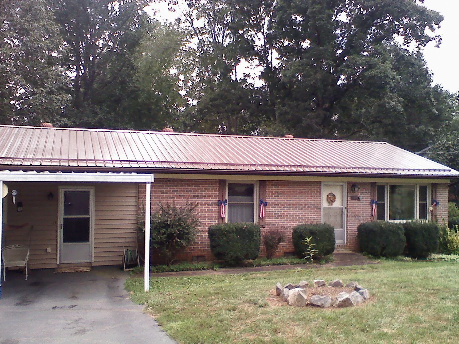Bronze metal roof and carport on a brick ranch home — Roof Repair work by our crew in Stover