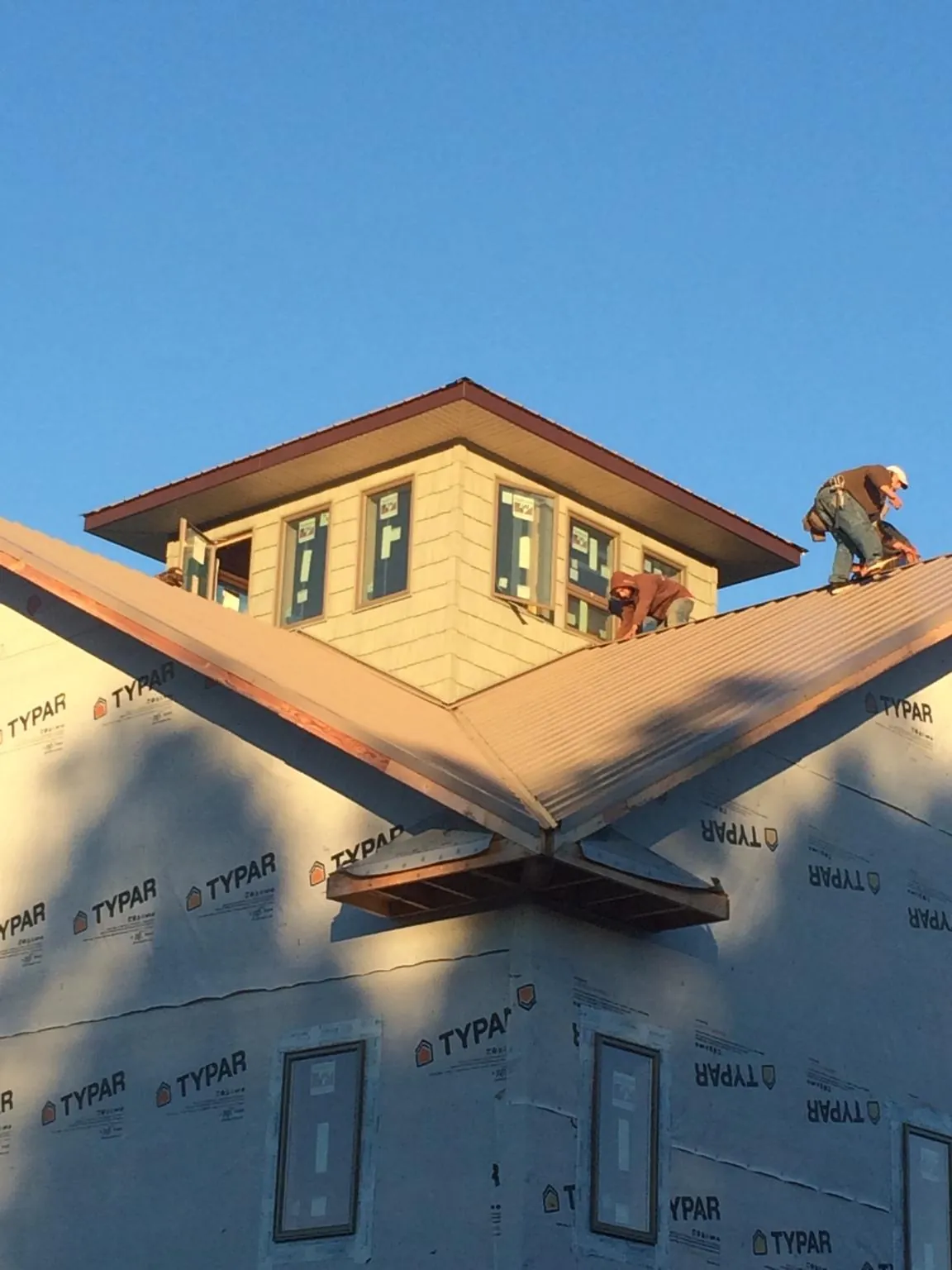 Roofers working around a rooftop cupola on a new metal roof at sunset — Roof Waterproofing in Stover by Roofing Brothers